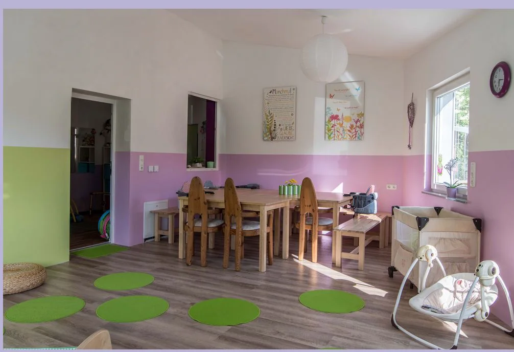 Heller Gemeinschaftsraum mit Esstischen und Platz für Babys und Kinder